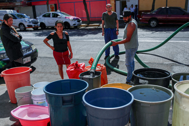 People fill buckets with water from a water tanker truck in the Azcapotzalco neighborhood in Mexico City on Jan. 26, 2024.