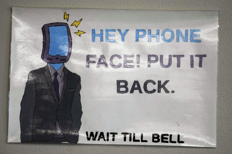 A sign in a classroom at Delta High School in Utah.At the rural Utah school, there is a strict policy requiring students to check their phones at the door when entering every class. Each classroom has a cellphone storage unit that looks like an over-the-door shoe bag with three dozen smartphone-sized slots. 