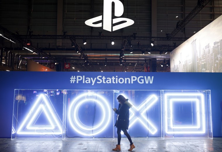 A woman walks past the Sony PlayStation Buttons Logo during 'Paris Games Week' in Paris