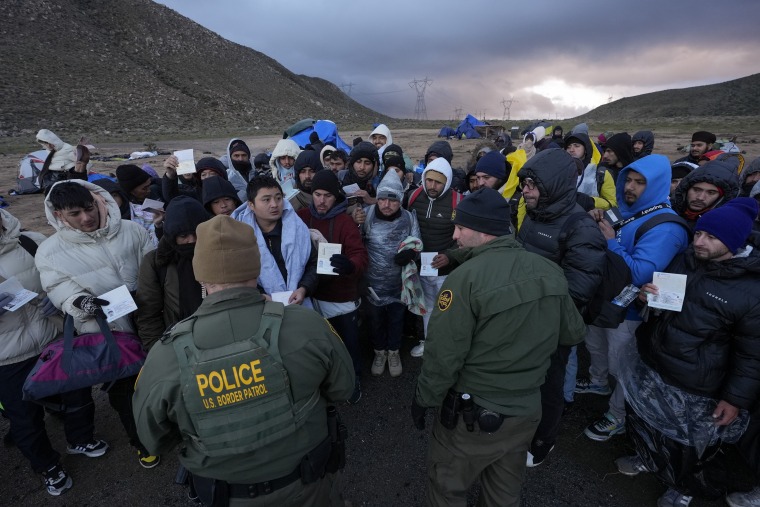 Agentes de la Patrulla Fronteriza hablan con migrantes que buscan asilo en un campamento montañoso improvisado después de cruzar la frontera desde México el viernes 2 de febrero de 2024, cerca de Jacumba, California.