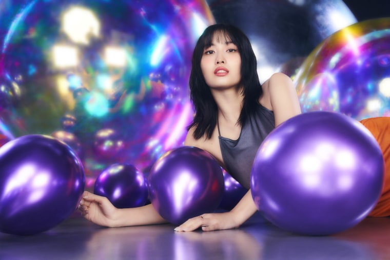 Bright photo shoot with TWICE member, Momo posing with giant and small shaped balloons on a dark background