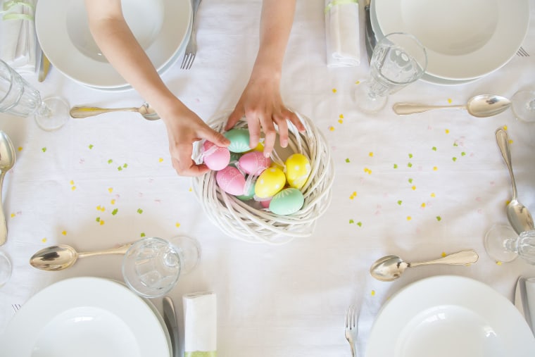 Little girl decorating dining table with Easter eggs