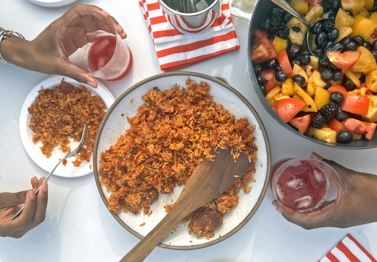 A traditional serving of jollof rice, ready to be enjoyed, with a side of refreshing mixed fruit salad, exemplifying the balance of spice and sweetness in West African meals.