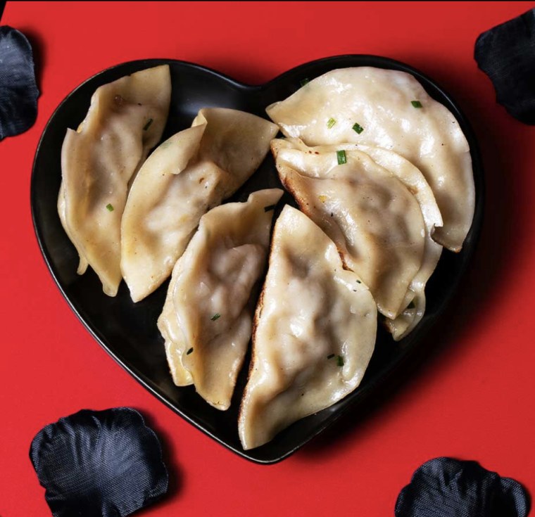 Dumplings on a heart plate against red background.
