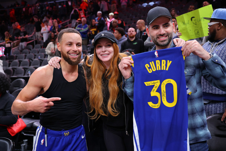 Stephen Curry #30 of the Golden State Warriors poses with actress Lindsay Lohan and her husband Bader Shammas after giving them his jersey in their 141-134 overtime loss to the Atlanta Hawks at State Farm Arena on February 03, 2024 in Atlanta, Georgia.