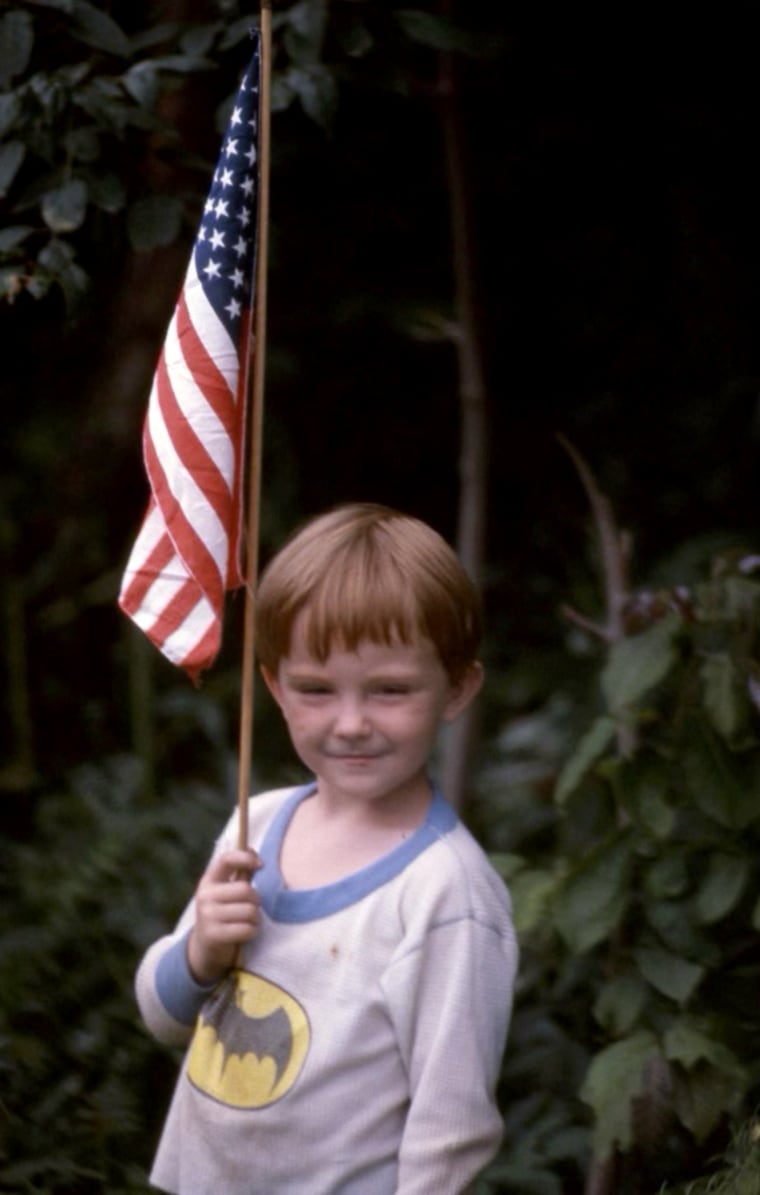 Image: Derek Scott as a young boy holding an American flag.