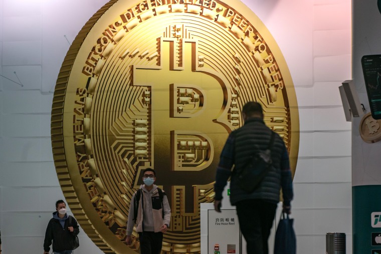 People walk past an ad for Bitcoin in Hong Kong