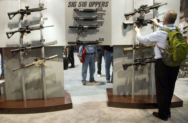 Image: A convention attendee looks at semiautomatic rifles at the National Shooting Sports Foundation's annual trade show in Las Vegas in 2013.