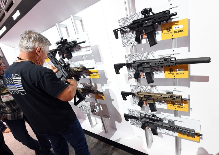 Image: A convention attendee looks at rifles at the National Shooting Sports Foundation's annual trade show in 2018 in Las Vegas.