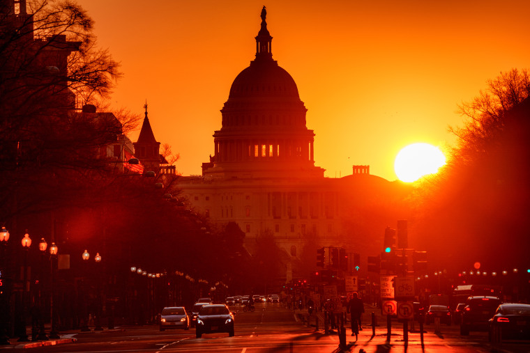 Traffic moves along Pennsylvania Avenue with the Capitol building in the background as the sun rises.