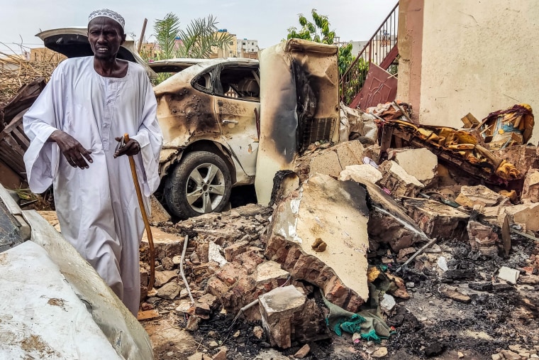 A man inspects damage as he walks through the rubble by a destroyed car outside a house that was hit by an artillery shell in southern  Khartoum in June.