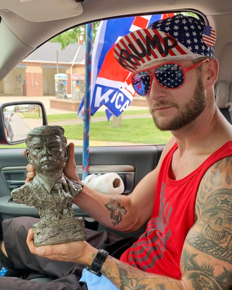 Lance Ligocki holds a statue while sitting in a car.