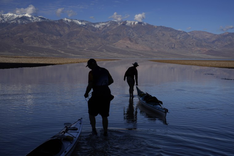 Brian Nelson, left, and Kathleen Nelson, right, pull kayaks into water at Badwater Basin in Death Valley National Park, Calif., on Feb. 22, 2024. 