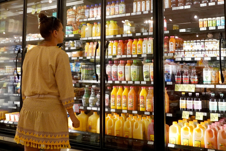 A woman looks at bottle of juice.