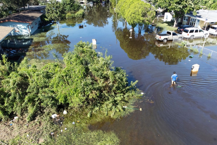 A aerial view of a man wading through a flooded street.