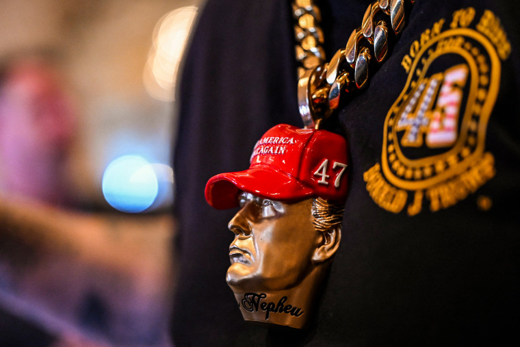 A supporter of Donald Trump wears a Trump bust jewelry.