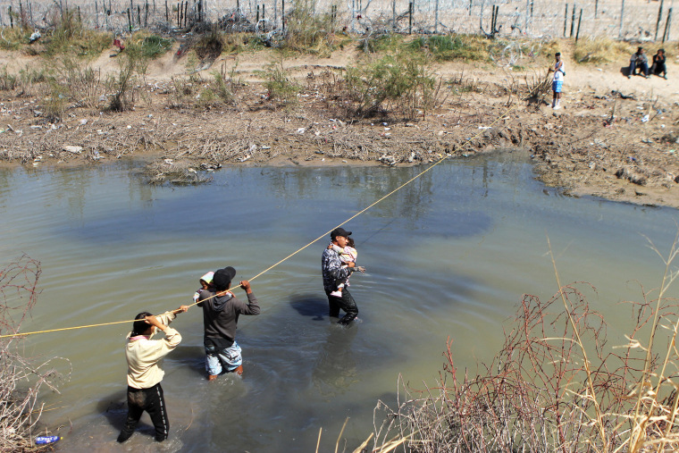 migrants water cross children carry