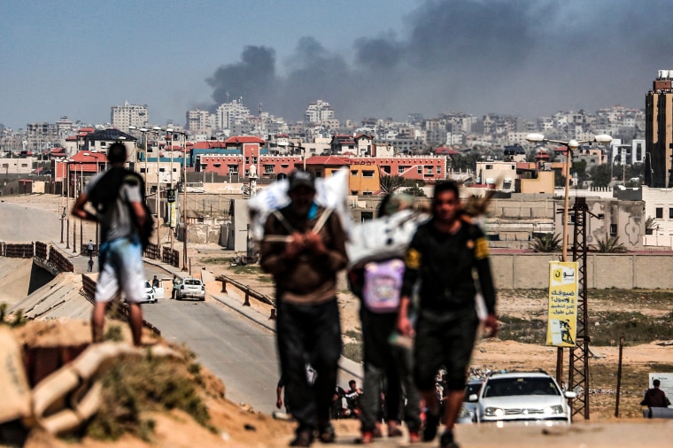 Image: Smoke rises above buildings during Israeli bombardment as people fleeing the Al-Shifa hospital