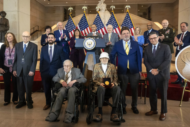 Ghost Army members John Christman, of Leesburg, N.J., second from left standing, Seymour Nussenbaum, of Monroe Township, N.J, in wheelchair at left, and Bernard Bluestein, of Hoffman Estates, Ill., in wheelchair at right, join military and congressional officials as members of their secretive WWII-era unit are presented with the Congressional Gold Medal during a ceremony on Capitol Hill, Thursday, March 21, 2024, in Washington. 