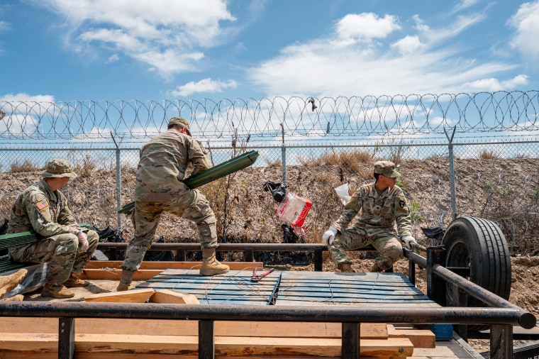 National Guard members lay materials out in preparation to build and repair damaged fencing on the banks of the Rio Grande near Shelby Park in Eagle Pass, Texas. 
