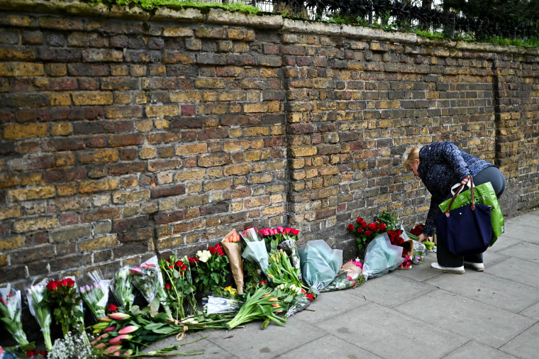 A person lays flowers outside the Russian embassy in London