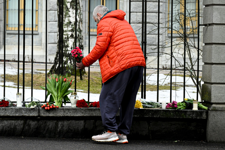 A man lays flowers at the fence of the Russian Embassy in Helsinki.
