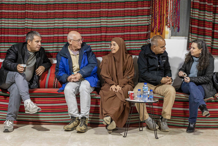 Huda Abu Obaid, center, and other guests, chat, while sitting.