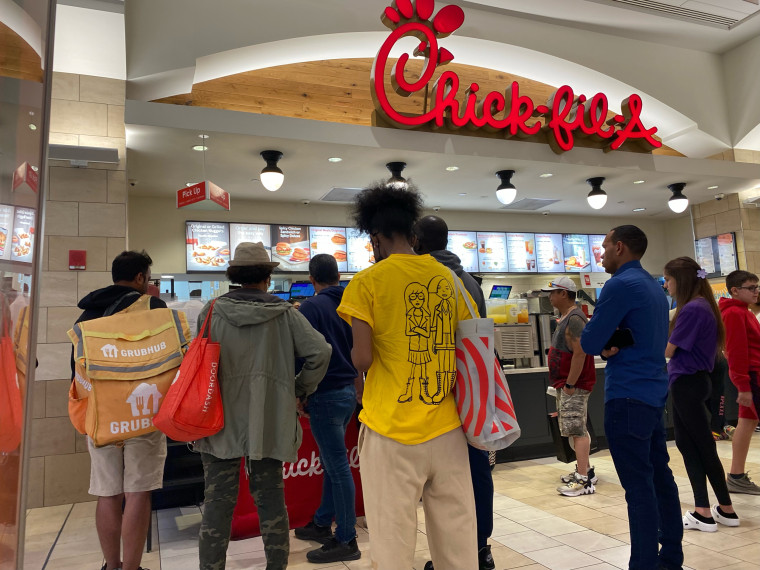 Chick-fil-A pick up area with many customers including Grub Hub and Door Dash delivery person waiting for orders, Queens Center Mall, Queens, New York