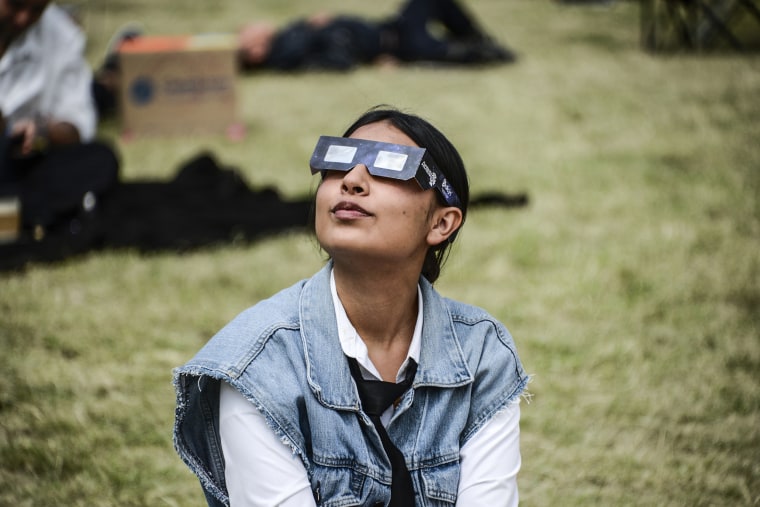 A woman watches the Annular Solar Eclipse with special sun filter glasses