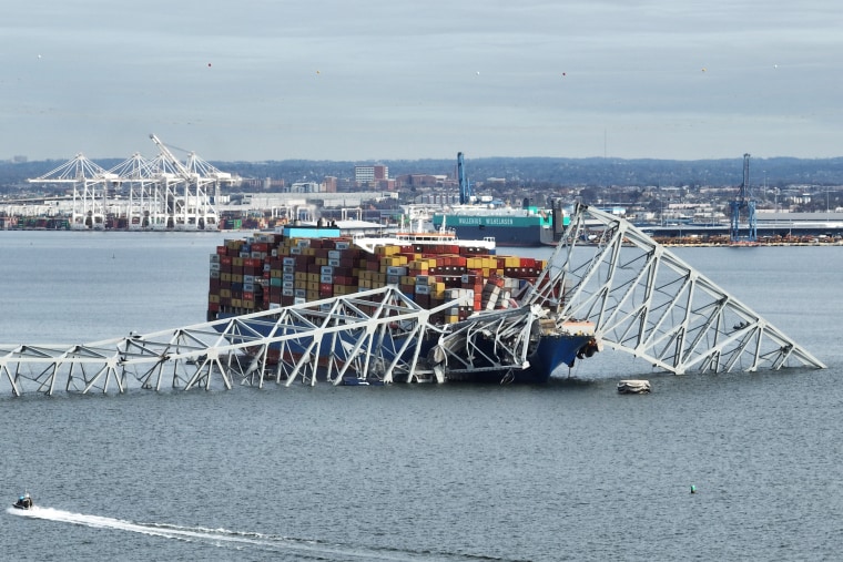 The steel frame of the collapsed Francis Scott Key Bridge sits on top of a container ship, in Baltimore