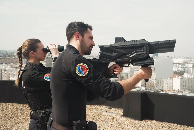 Beamte führen von einem Dach in Paris aus ein Watson-Drohnengewehr vor. 