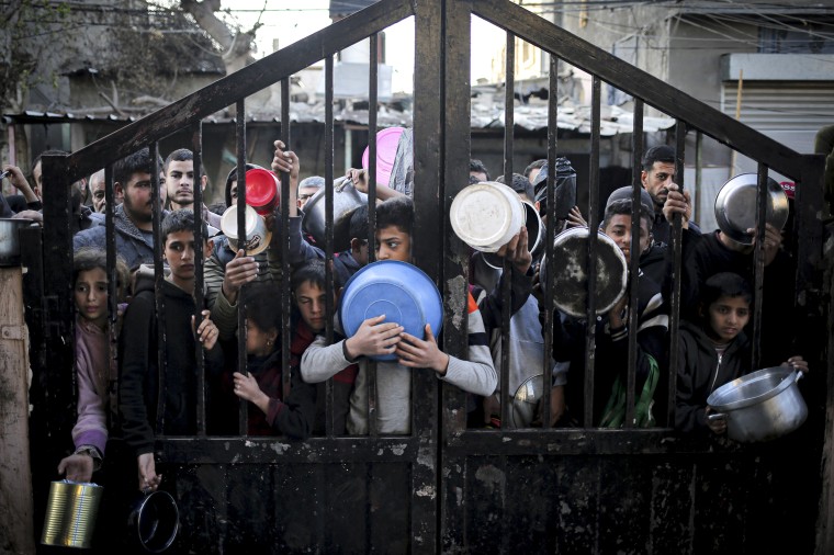 Displaced Palestinians gather to collect food