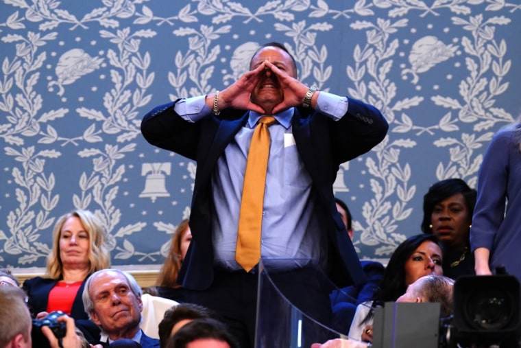 Un hombre grita desde la sala durante el discurso de Biden.