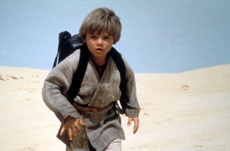 JAKE LLOYD wears a backpack in a desert scene as a young Anakin skywalker.