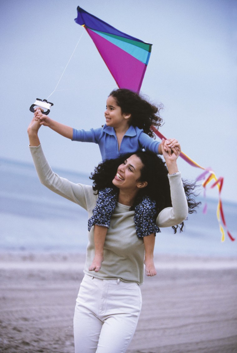 mother and daughter flying at kite at beach