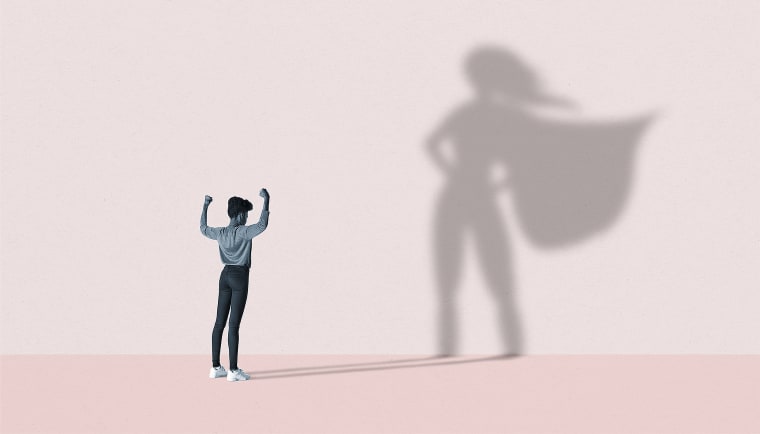 Woman flexing muscles in front of superhero shadow