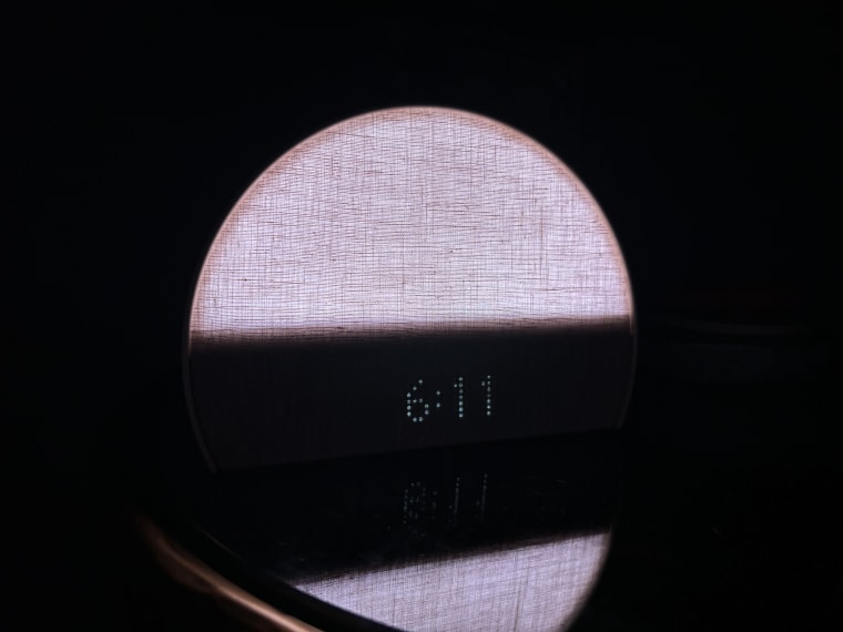 The Hatch Restore 2 sunrise alarm clock lit pink, displaying the time 6:11 a.m