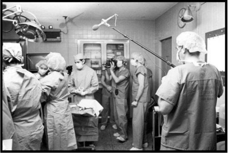 Medical providers and members of the media filming a documentary about Carr's birth stand in an operating room.