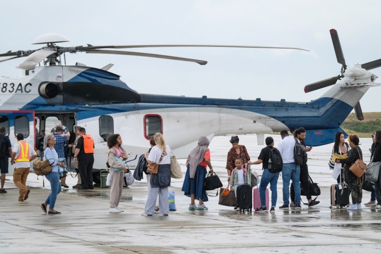 People evacuated from Haiti by a U.S. helicopter arrive at Las Americas airport