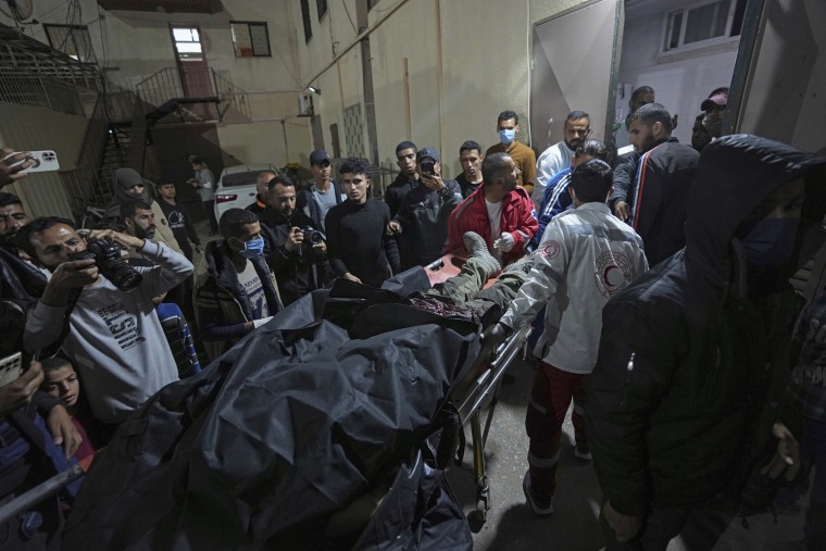 Palestinians carry the body of a person following an Israeli airstrike into the Al Aqsa hospital in Deir al Balah, Gaza Strip, on April 1, 2024. 