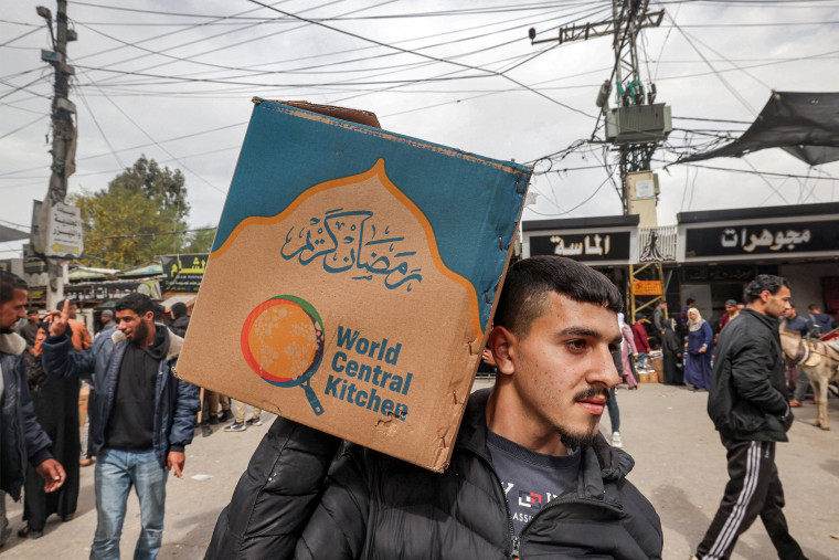 A man carries a cardboard box of food aid provided by World Central Kitchen in Rafah, Gaza
