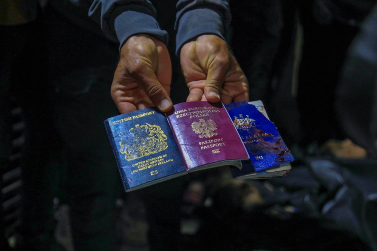 A man displays British, Polish, and Australian passports next to the bodies of World Central Kitchen workers at Al-Aqsa Hospital in Deir al-Balah, Gaza, on April 1, 2024.