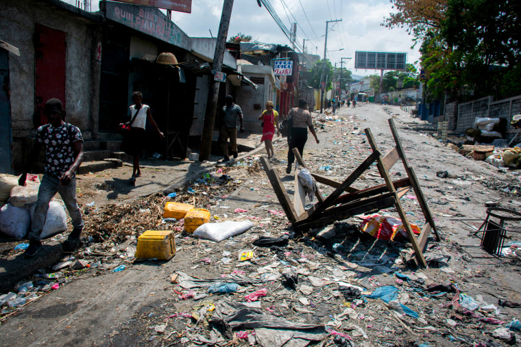 People walk past a barricade in a road in Port-au-Prince.