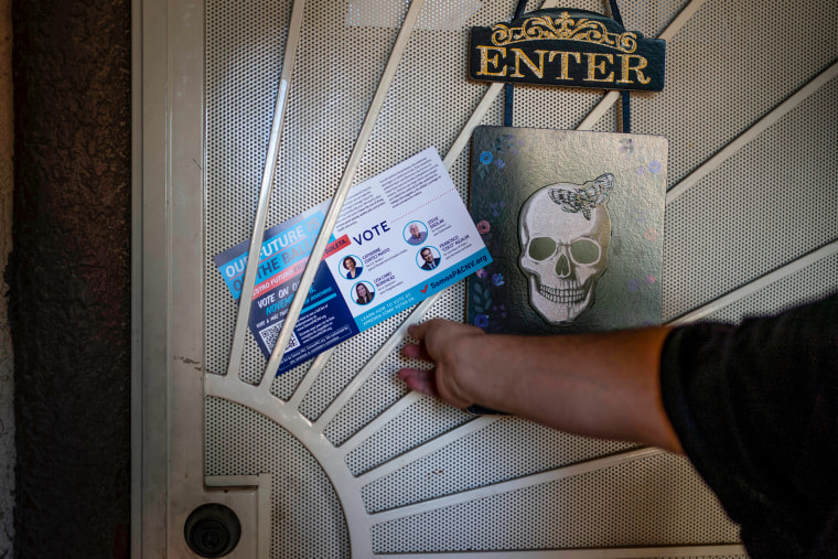 Victor Villenueva puts a flyer on a Nevada voter's door