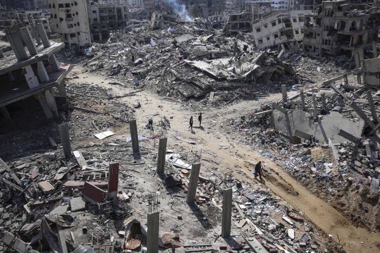 Palestinians walk amid the destruction in the vicinity of al-Shifa Hospital, following a two-week military operation by the Israeli army in Gaza City, on April 2, 2024.  