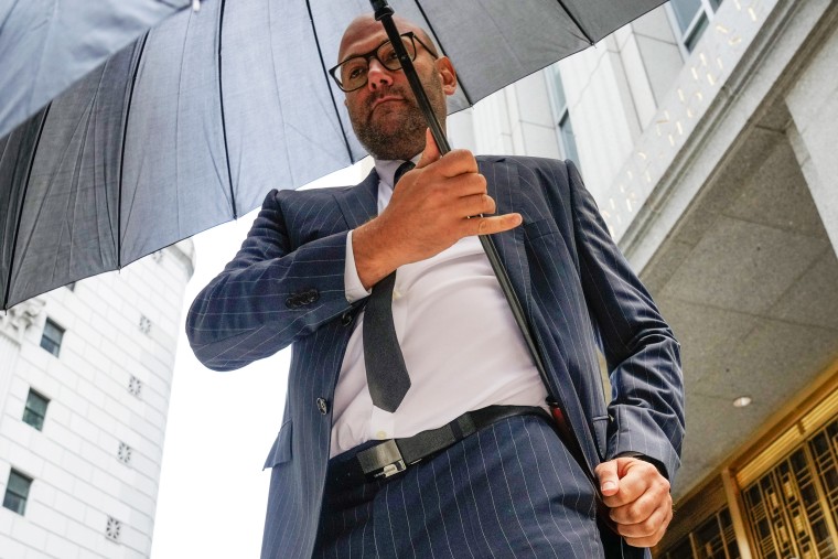 Gerald Shvartsman hides from photojournalists with an umbrella after exiting Federal Court in 2023.