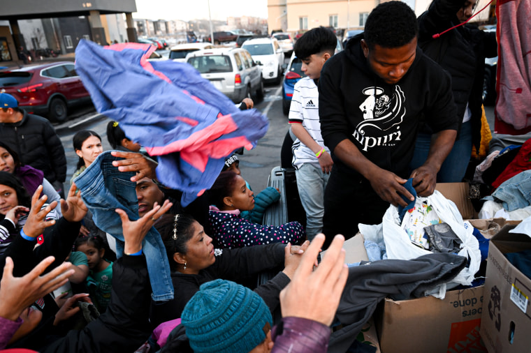 Migrants hand out donated clothes to other migrants.