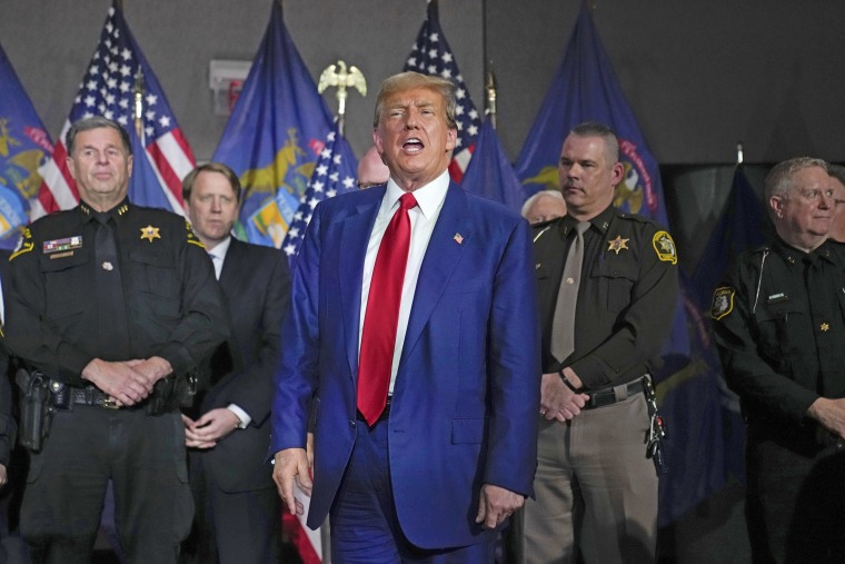 Former President Donald Trump is surrounded by law enforcement officers at a campaign event in Grand Rapids, Mich., Tuesday, April 2, 2024.