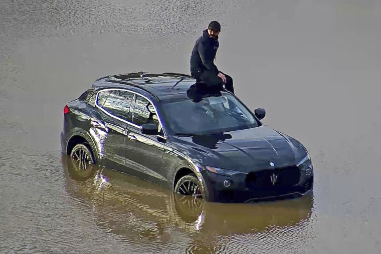 A man is stranded on his vehicle in floodwaters in Columbus, Ohio, on April 3, 2024. 