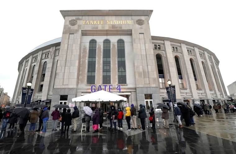 People line up in the rain outside the Yankee Stadium in New York